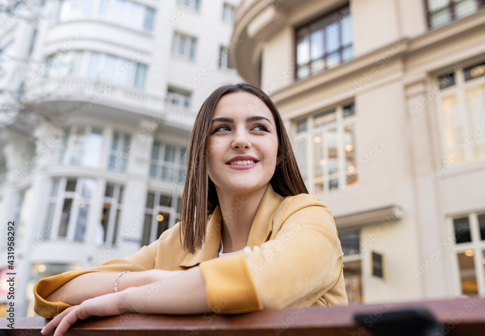 Smiling young woman with brown hair looking away in front of building Smiling young woman with brown hair looking away in front of building