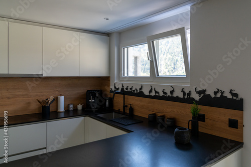 interior view of a modern and elegant kitchen with white cupboards and black tiles