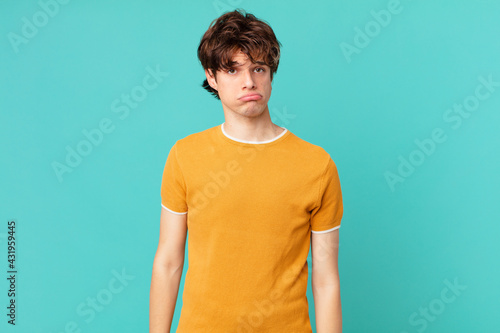 young handsome man feeling sad and whiney with an unhappy look and crying photo