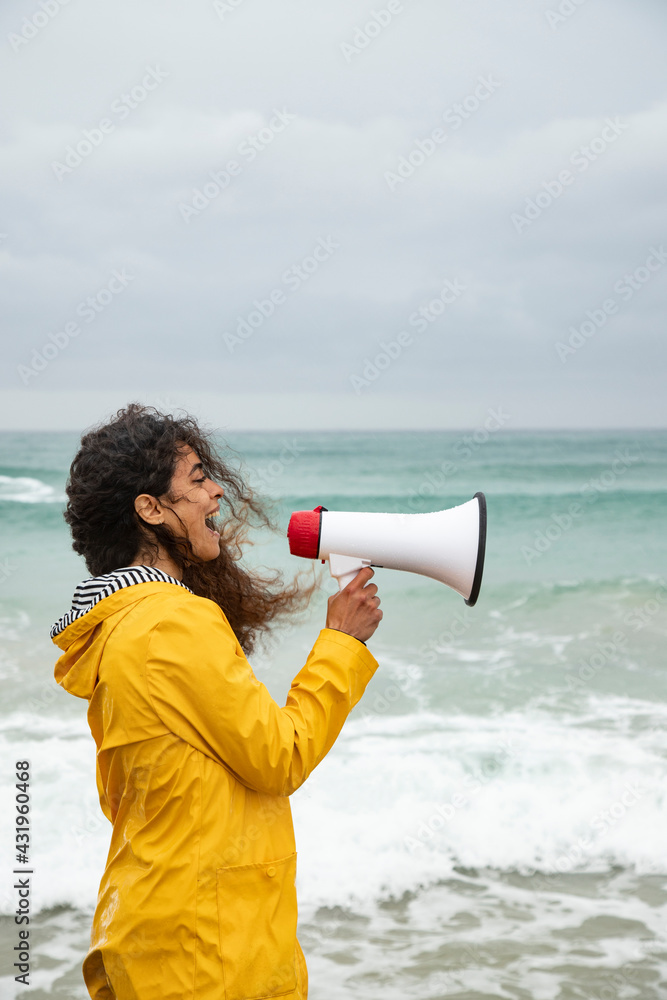 Woman screaming in megaphone while standing at beach Woman screaming in megaphone while standing at beach