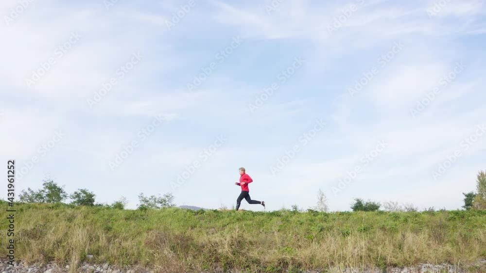 Slow-motion: man wearing black running pants and red sweatshirt running on a blue sky background. Sports, running concept. Slow-motion: man wearing black running pants and red sweatshirt running on a blue sky background. Sports, running concept.