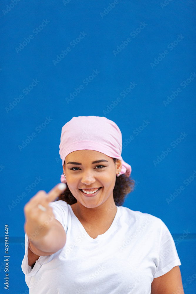 Smiling woman doing obscene gesture against wall Smiling woman doing obscene gesture against wall