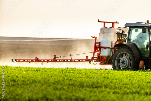 Young farmer in tractor spraying insecticide in green farm photo
