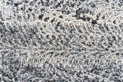 Multiple traces of car tires in the snow on the asphalt. Close up view from above