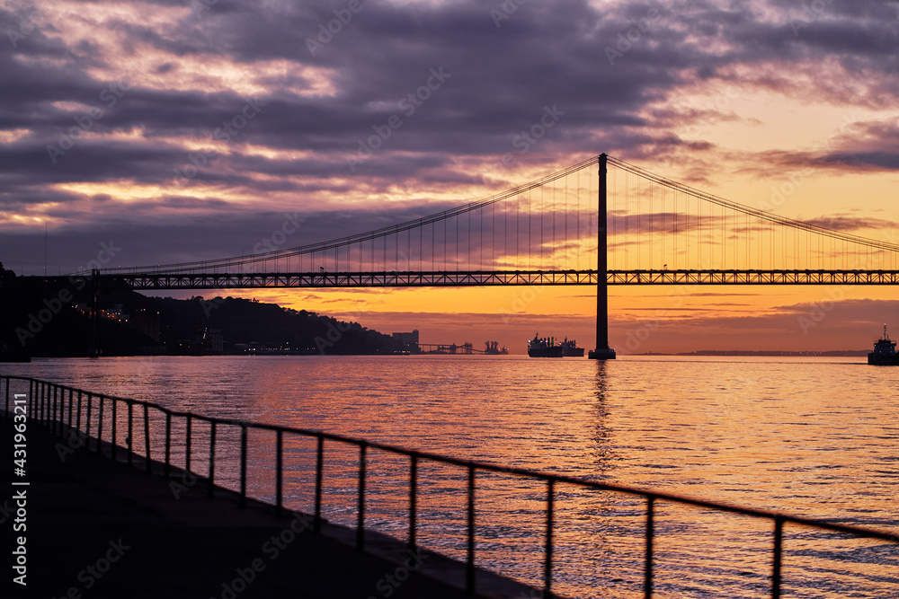Beautiful landscape with suspension 25 April bridge bridge over the Tagus river in Lisbon at sunset.