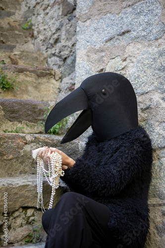 Woman in crow costume looking at jewelry by staircase photo