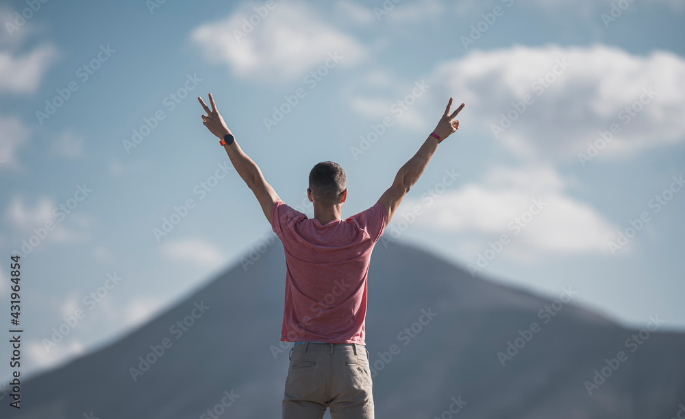 Male tourist with arms raised gesturing peace at Lanzarote on sunny day, Spain Male tourist with arms raised gesturing peace at Lanzarote on sunny day, Spain