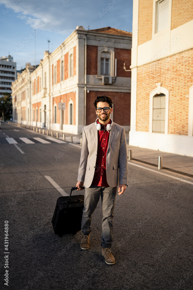 Smiling male entrepreneur with suitcase walking on road Smiling male entrepreneur with suitcase walking on road