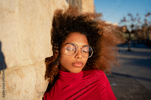 Young woman with eyes closed leaning on wall