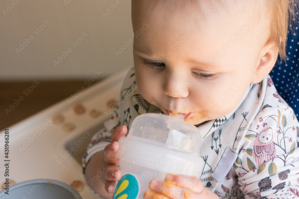 Young toddler learning to use a straw cup to drink water; promoting lip