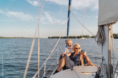 Romantic vacation and luxury travel. Senior loving couple sitting on the yacht deck. Sailing the river. © luengo_ua