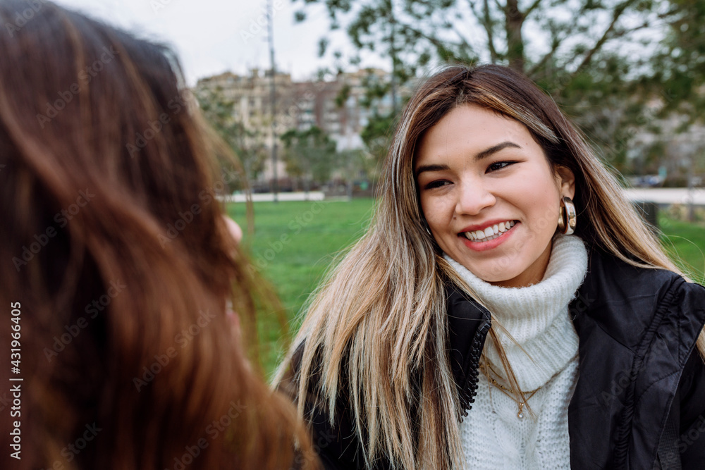 Smiling young woman with female friend at public park Smiling young woman with female friend at public park