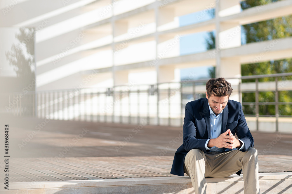 Businessman smiling while sitting on steps during sunny day Businessman smiling while sitting on steps during sunny day