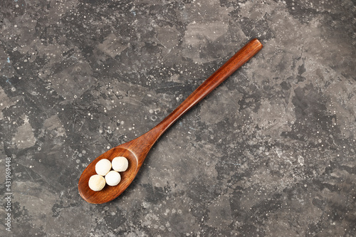 Traditional asian dry smoked kurut cheese in a wooden eco friendly spoon on a dark background copy photo