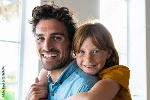 Smiling daughter embracing cheerful father at home photo