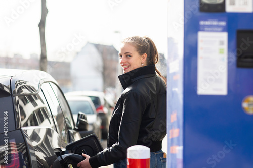 Portrait of young beautiful blonde refueling car at gas station photo