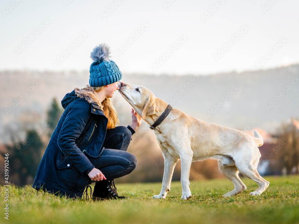 Young woman in knit hat playing with dog in field Young woman in knit hat playing with dog in field