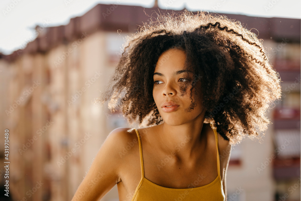 Beautiful woman with black frizzy hair looking away during sunny day Beautiful woman with black frizzy hair looking away during sunny day