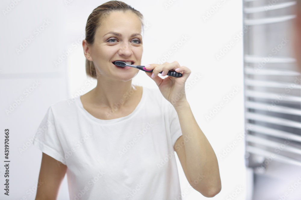 Smiling woman brushes her teeth in front of mirror Smiling woman brushes her teeth in front of mirror