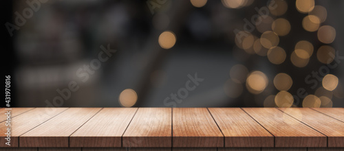 Empty wooden table top with lights bokeh on blur restaurant background.