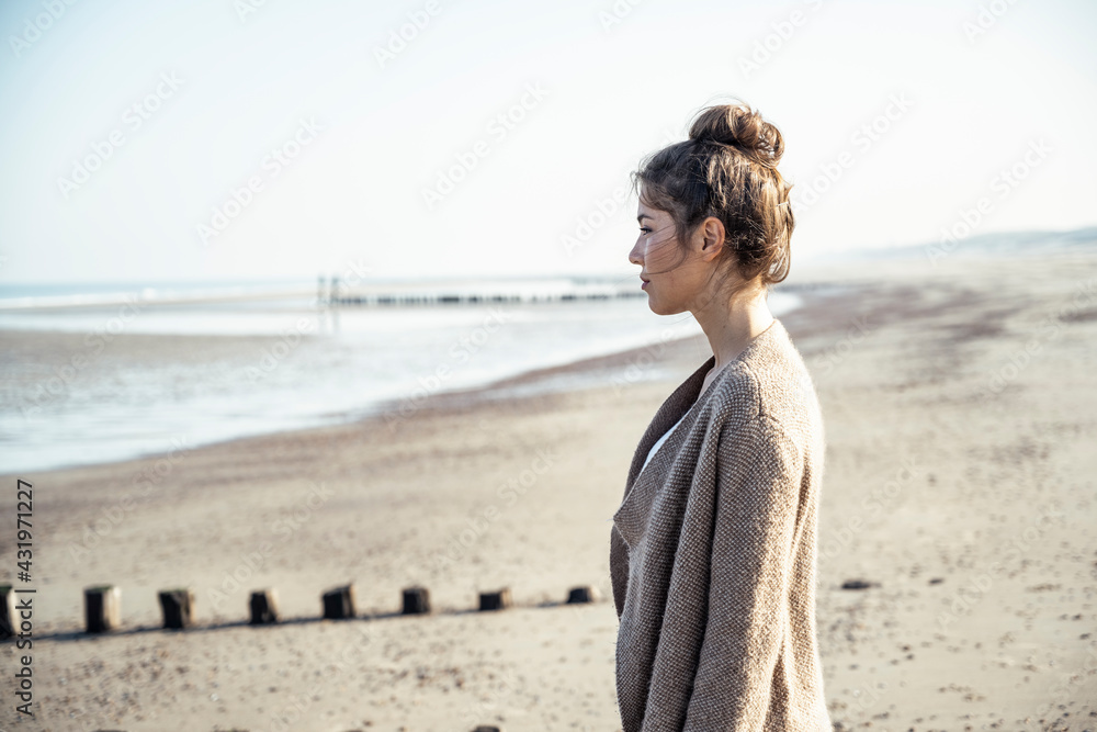 Young woman contemplating while standing on beach during sunny day Young woman contemplating while standing on beach during sunny day