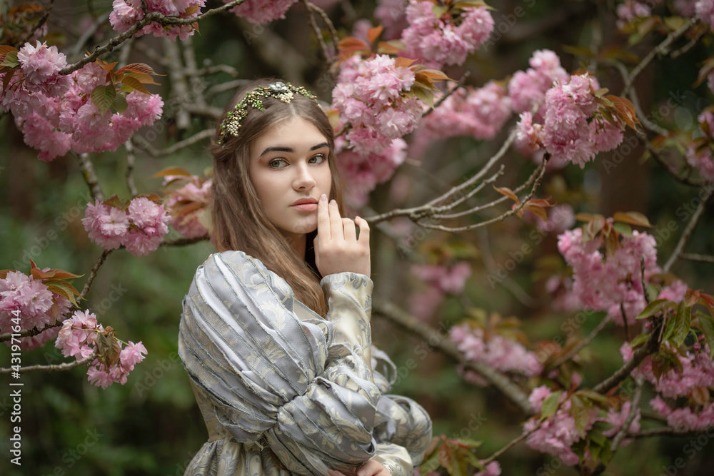 Fototapeta premium Young maiden in a medieval dress with sakura blossoms
