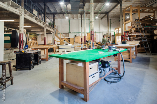 Male coworkers operating machinery in carpentry workshop