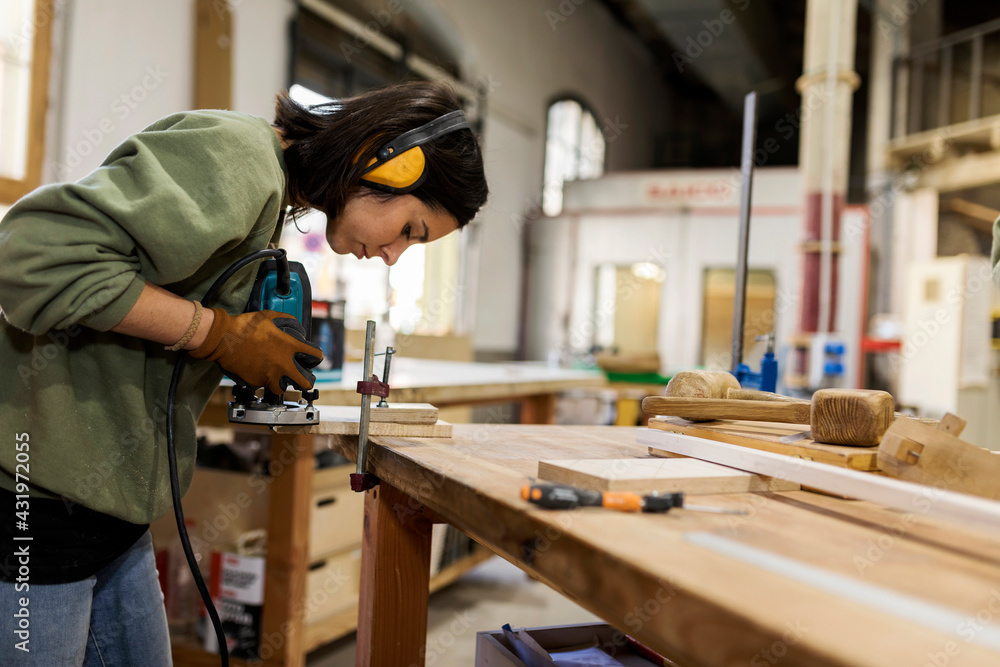 Craftswoman working with router jig at workbench in workshop Craftswoman working with router jig at workbench in workshop
