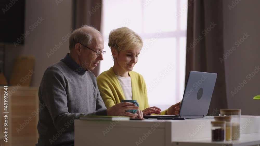 online shopping from home, old man and woman are viewing goods on internet store site sitting at kitchen online shopping from home, old man and woman are viewing goods on internet store site sitting at kitchen