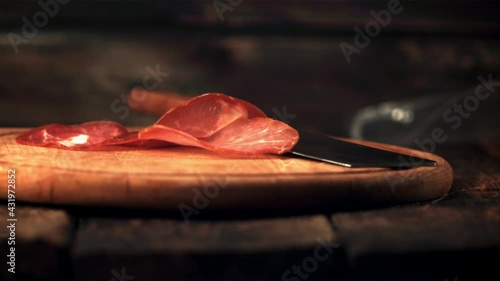 Super slow motion fragrant pieces of dried meat fall on the cutting board. On a wooden background.Filmed on a high-speed camera at 1000 fps. photo