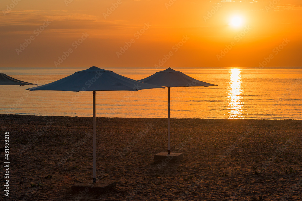 Row of beach umbrellas on a sandy beach by the sea in the morning