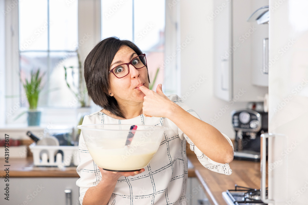 Happy woman licking cake filling from her finger Happy woman licking cake filling from her finger