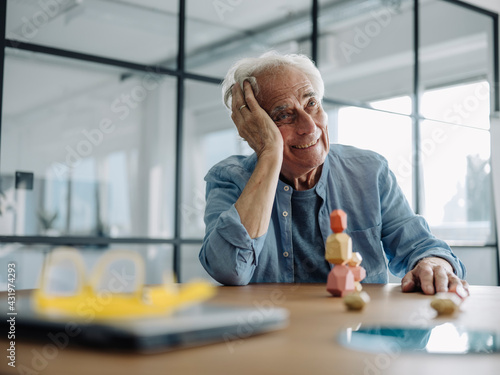 Smiling businessman with head in hands looking away while sitting at office photo