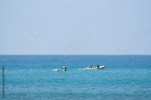 Rybak na kutrze, płynący na otwartym oceanie, kolorowa motorówka na niebieskiej wodzie. © insomniafoto