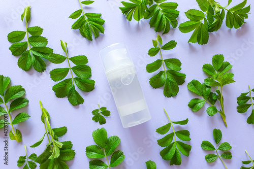 Transparent bottle of intimate lubricant gel and fresh green leaves on light purple backgroundl. Intimate massage, comfortable sex. Lifestyle, flat lay, mockup. Unbranded bottle for branding