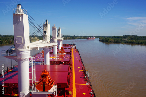 Vessel proceeding up the Parana River. Type of ship: Bulk carrier with cranes. Another ship is steaming in the opposite direction. Rio Parana.