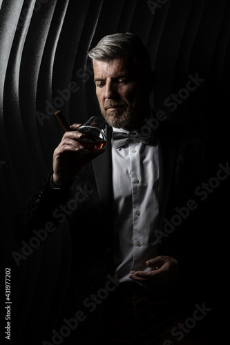 Portrait of a gentleman observing his glass of alcohol
