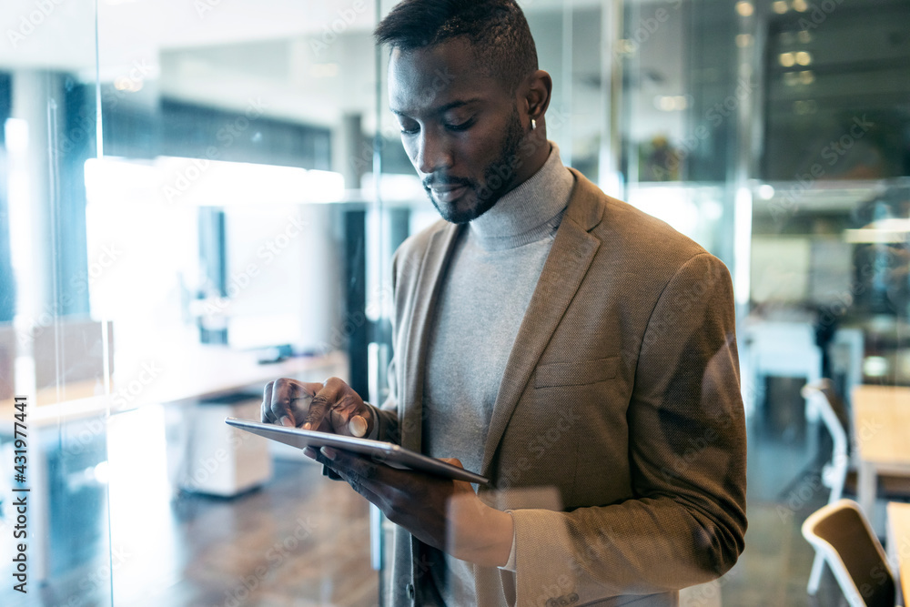 Entrepreneur using digital tablet while standing in office Entrepreneur using digital tablet while standing in office