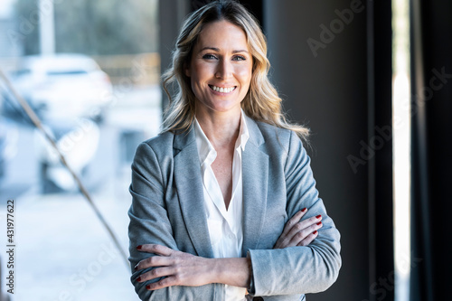 Confident businesswoman smiling while standing at office photo