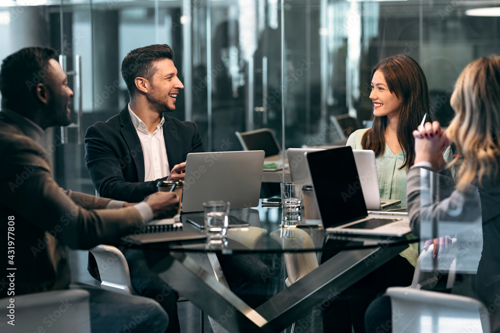 Smiling business people having discussion in meeting while sitting at office Smiling business people having discussion in meeting while sitting at office