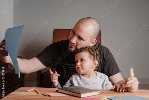 Dad and son reviewing a sheet with painted pictures. Learning at home photo