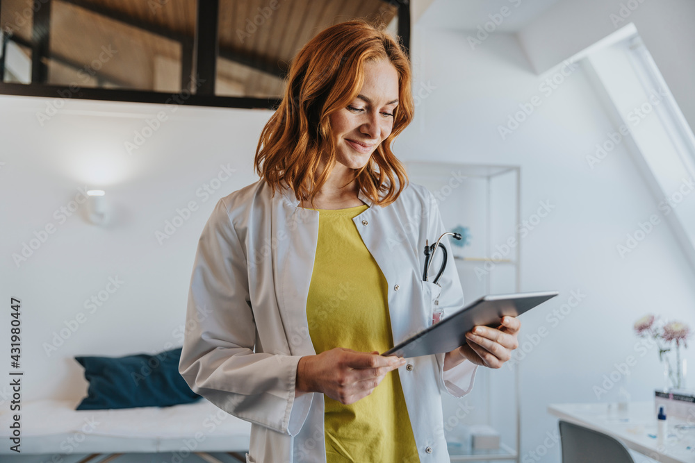 © Mareen Fischinger/Westend61 - Mid adult doctor using digital tablet while standing at clinic