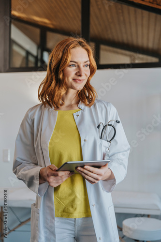 General practitioner with digital tablet standing at clinic