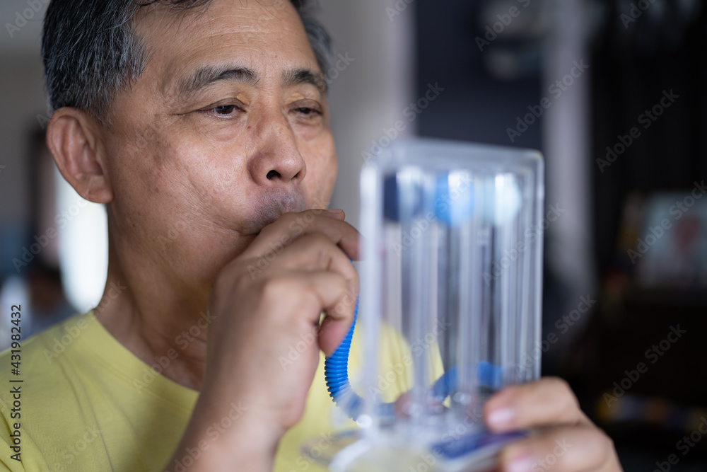 Old man uses a Tri-ball Incentive Spirometer for check his lung function. Old man uses a Tri-ball Incentive Spirometer for check his lung function.