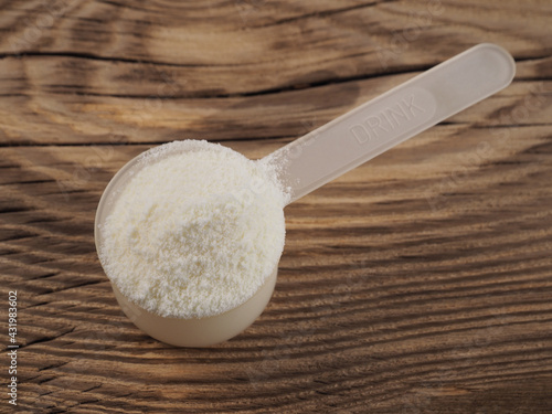 Obraz na plátne Protein powder, chondroitin, glucosamine in a plastic spoon for making a high-calorie drink on a wooden background, closeup, flat layout