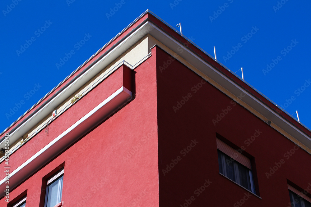 Urban construction in Rome, residential building, painted dark red, blue sky.