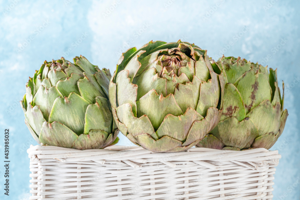 Obraz premium closeup ripe artichokes in a basket over blue