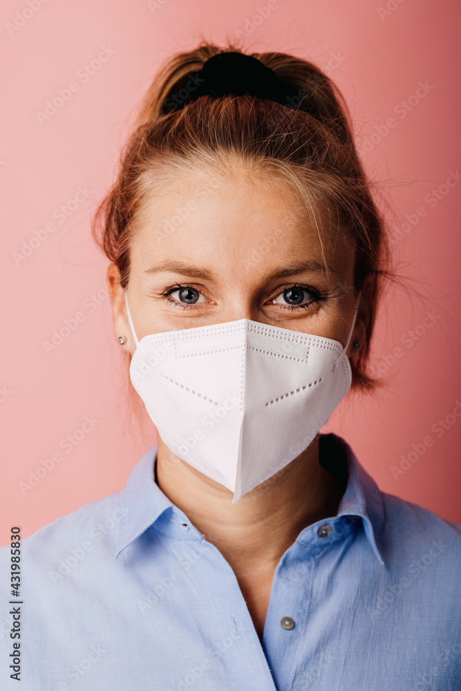 Mid adult businesswoman wearing protective face mask standing against colored background Mid adult businesswoman wearing protective face mask standing against colored background