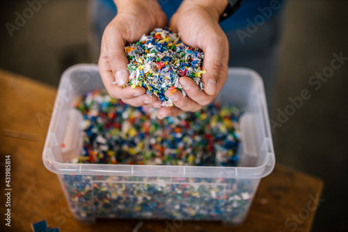 Man with container holding recycled plastic in factory photo