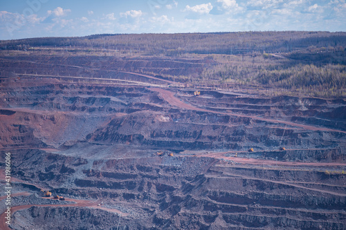 View of a part of an iron ore quarry with various shades of pink and blue quartzite and terraces for the removal of ore. Background. © Roman